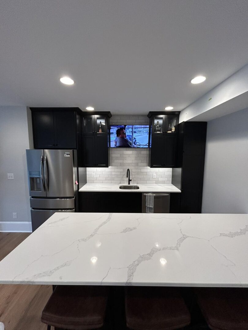 Modern kitchen with marble island and TV.