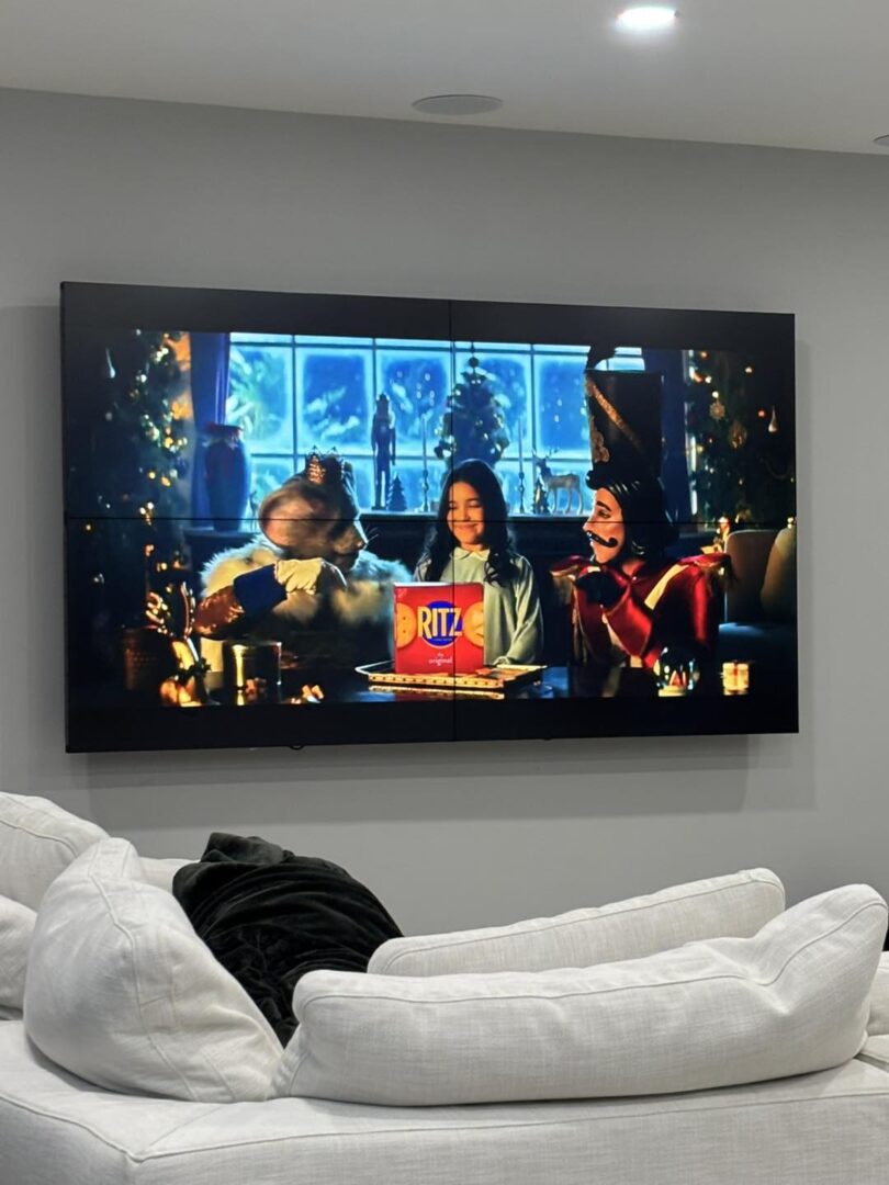 People watching TV with holiday scene displayed.