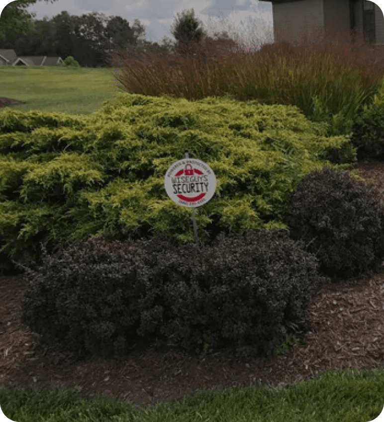 Security sign in garden with shrubs.