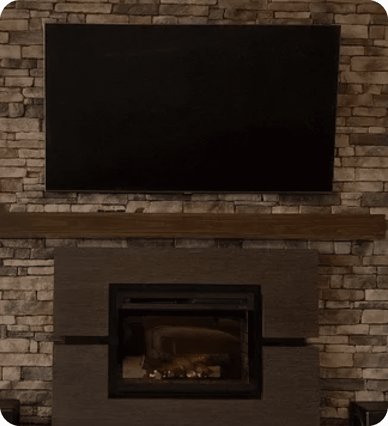 TV above fireplace on stone wall.