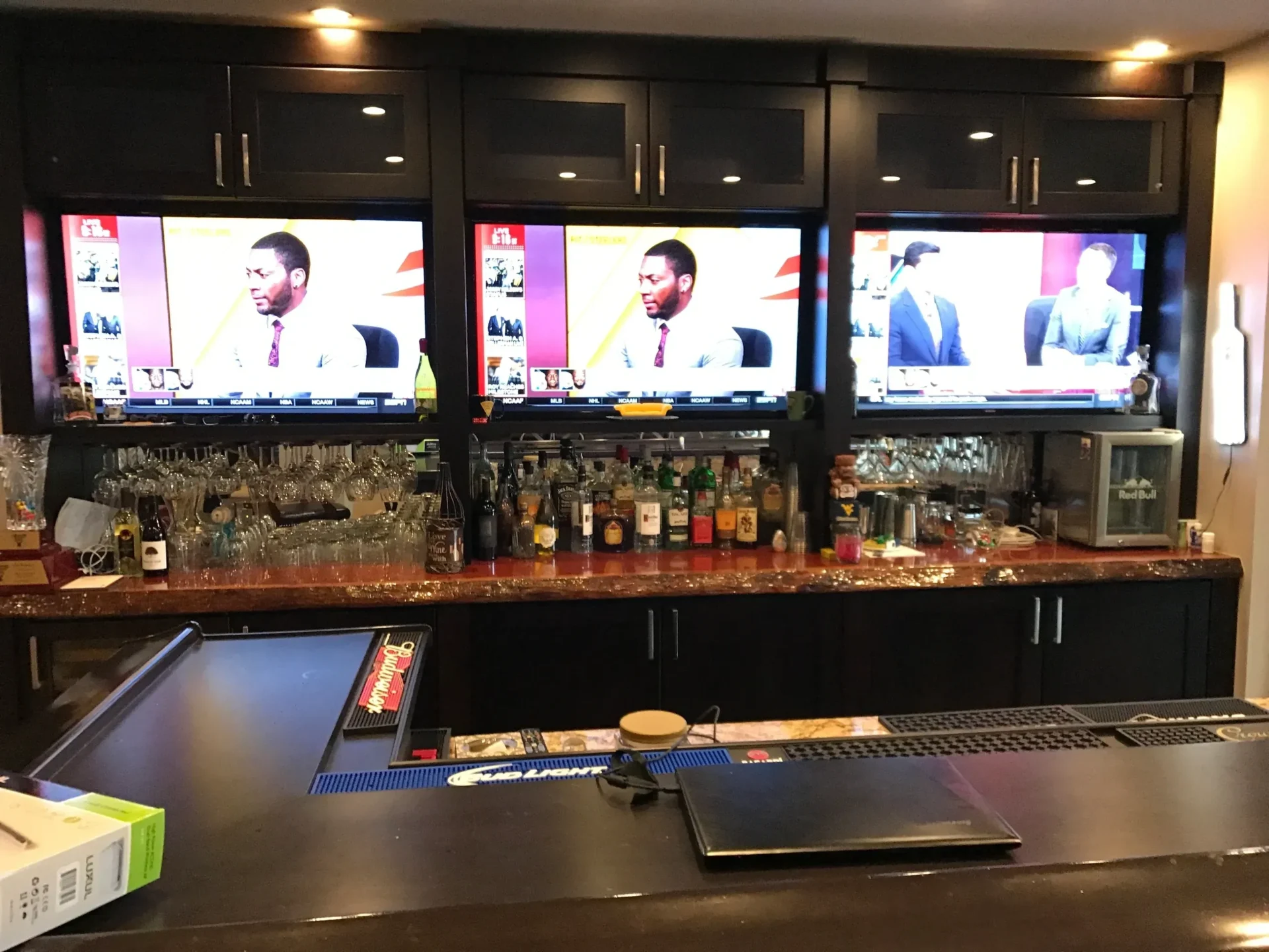 Bar counter with three mounted televisions.