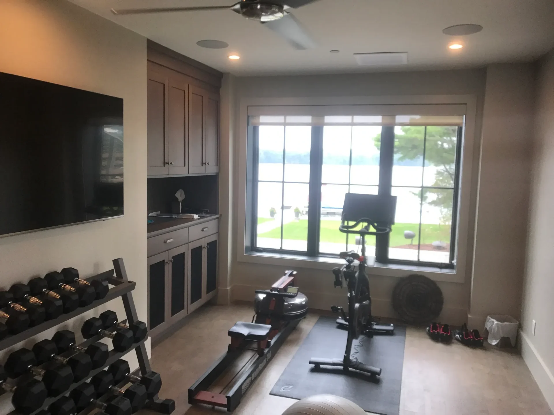Home gym with equipment and lakeside view.