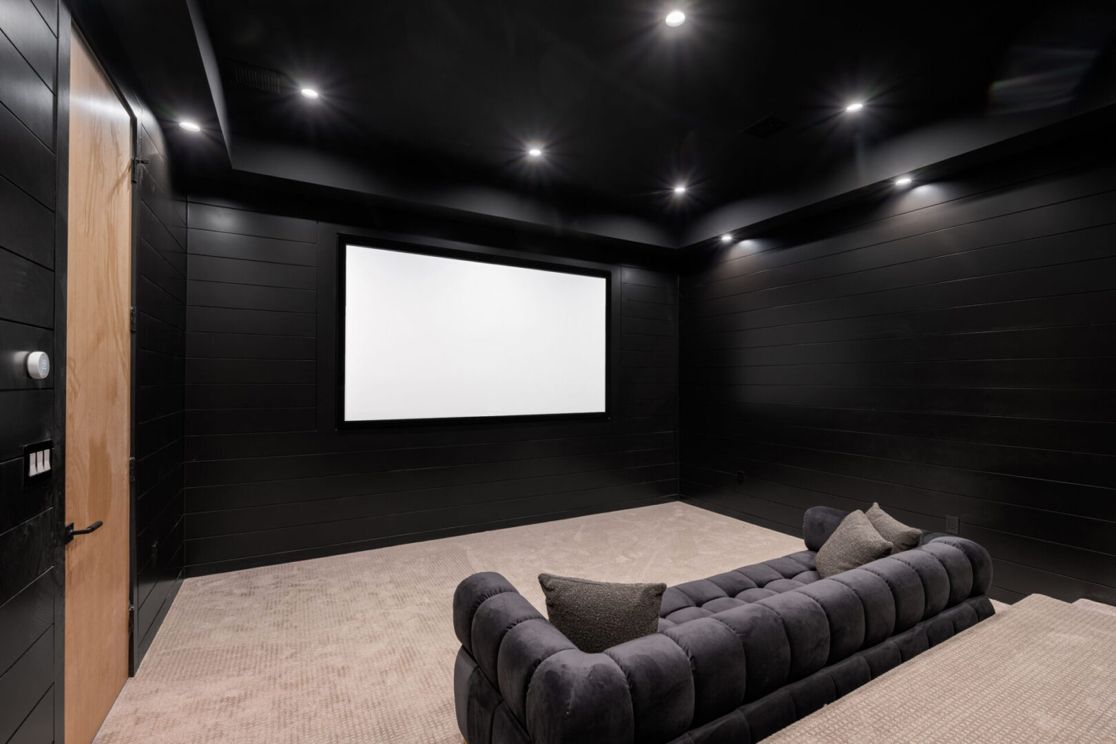 Modern home theater with black walls and plush seating.