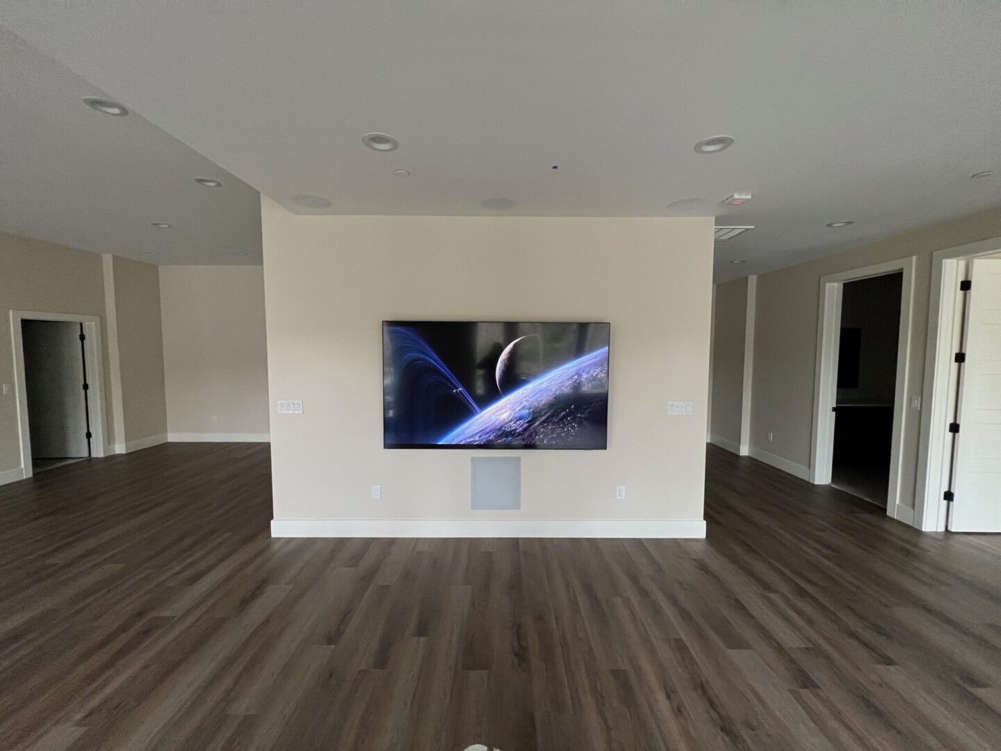 Modern living room with wall-mounted TV and wood flooring.