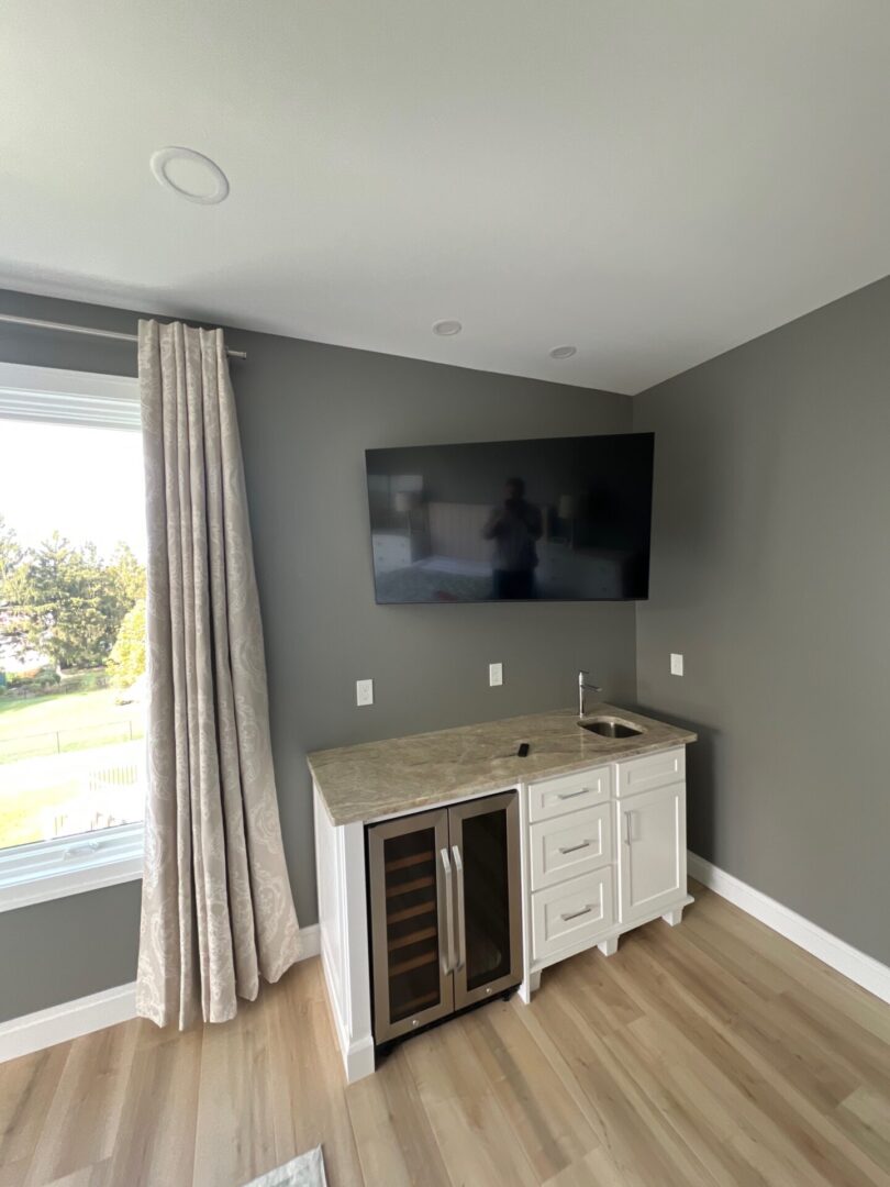 Corner TV setup with a mounted screen and white cabinet.